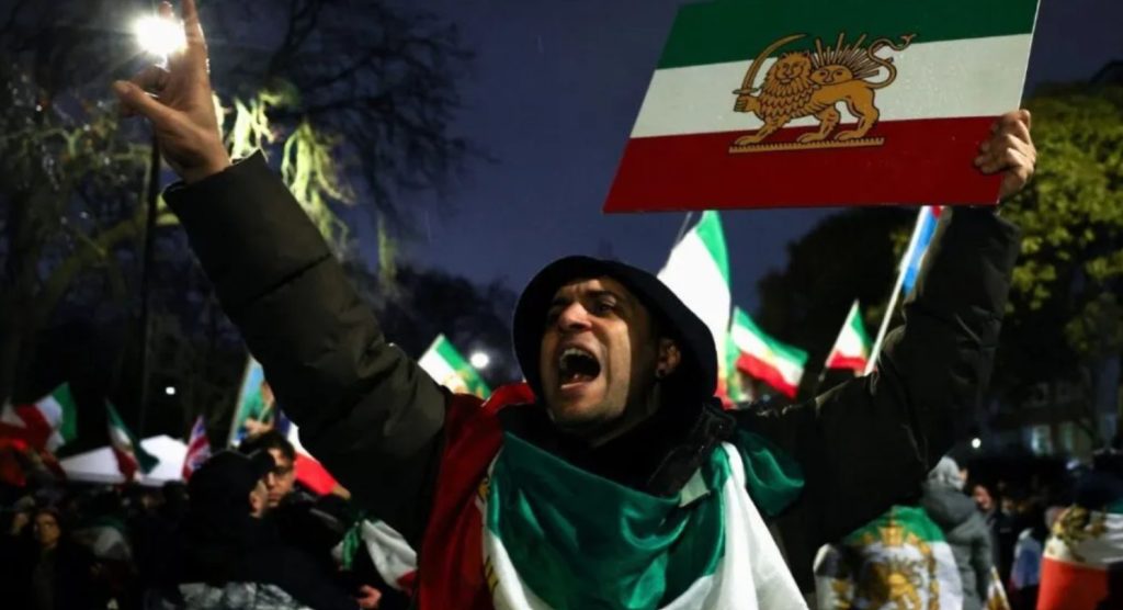 İran'lı protestocu, eski rejim bayrağıyla