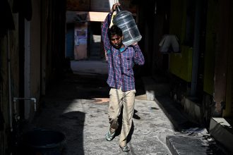 Hindistan'da temel insani şartlardan yoksun yaşayan işçiler evlerine çeşmelerden su taşıyorlar.