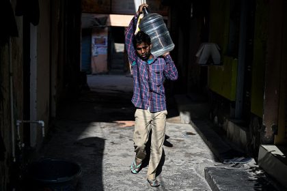 Hindistan'da temel insani şartlardan yoksun yaşayan işçiler evlerine çeşmelerden su taşıyorlar.